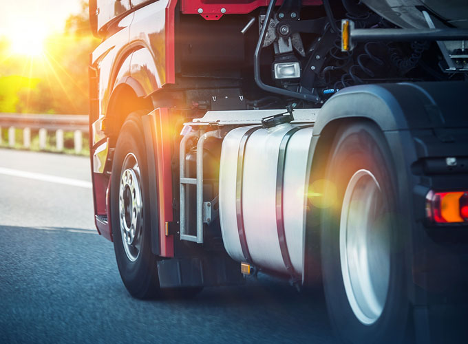 Seitliche Detailaufnahme eines LKW, der in Richtung der Sonne fährt – Einsatz von Präzisionsteilen der Martin Höhn GmbH im Nutzfahrzeugbereich