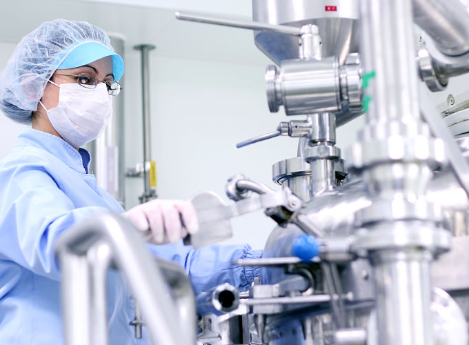Frau in Schutzkleidung bedient eine Anlage der Pharmaindustrie – Einsatzbereich für Präzisionsteile der Martin Höhn GmbH