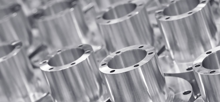 Zahlreiche Frästeile aus Metall, ordentlich nebeneinander aufgereiht, Detailaufnahme.