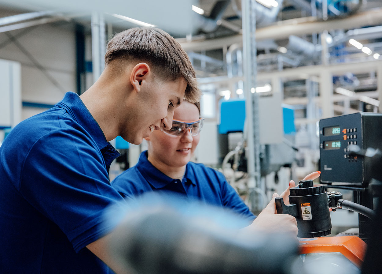 Zwei Ferienjobber an einer CNC-Drehmaschine.